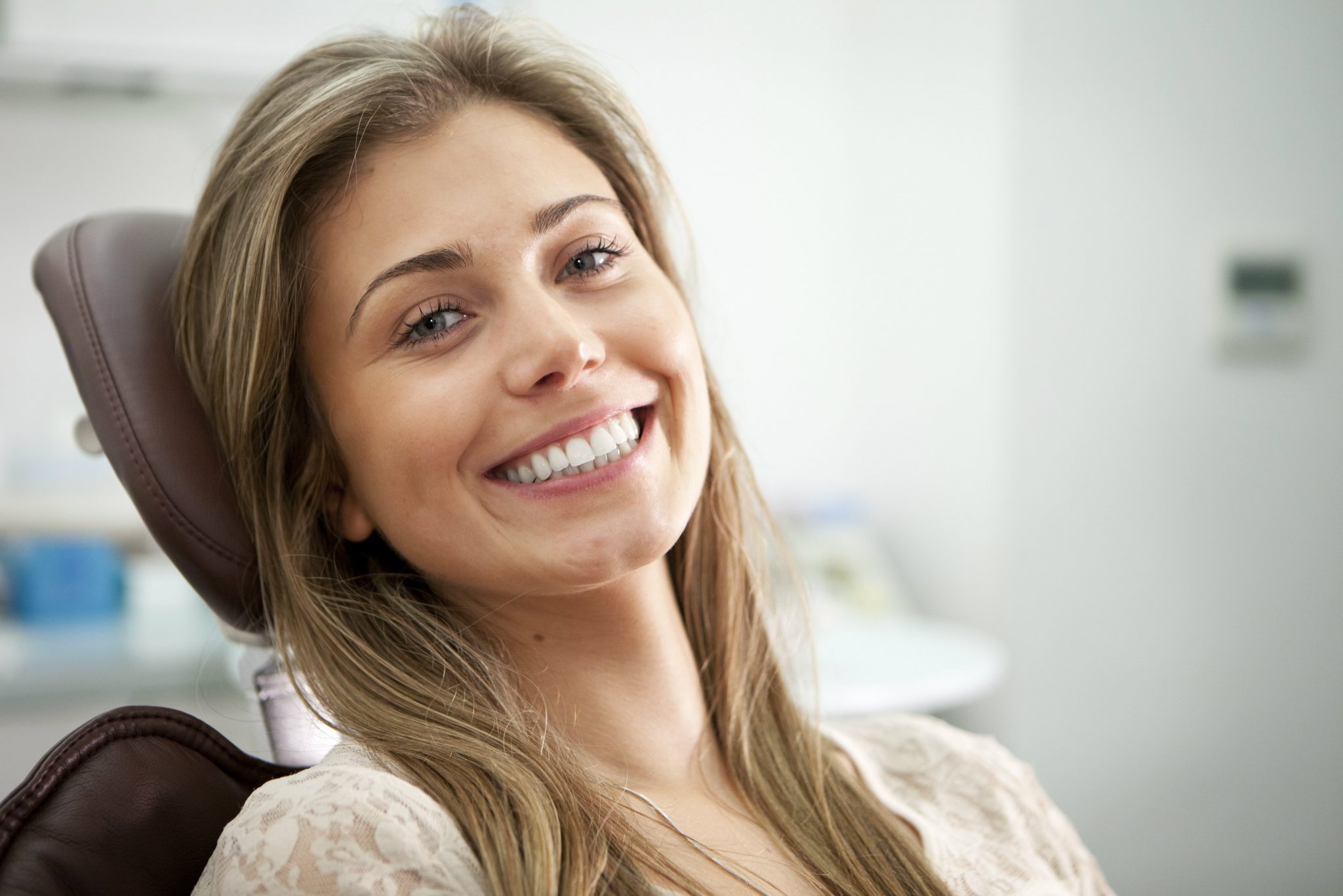 woman-smiling-while-sitting-with-head-laid-back-on-dentist-chair